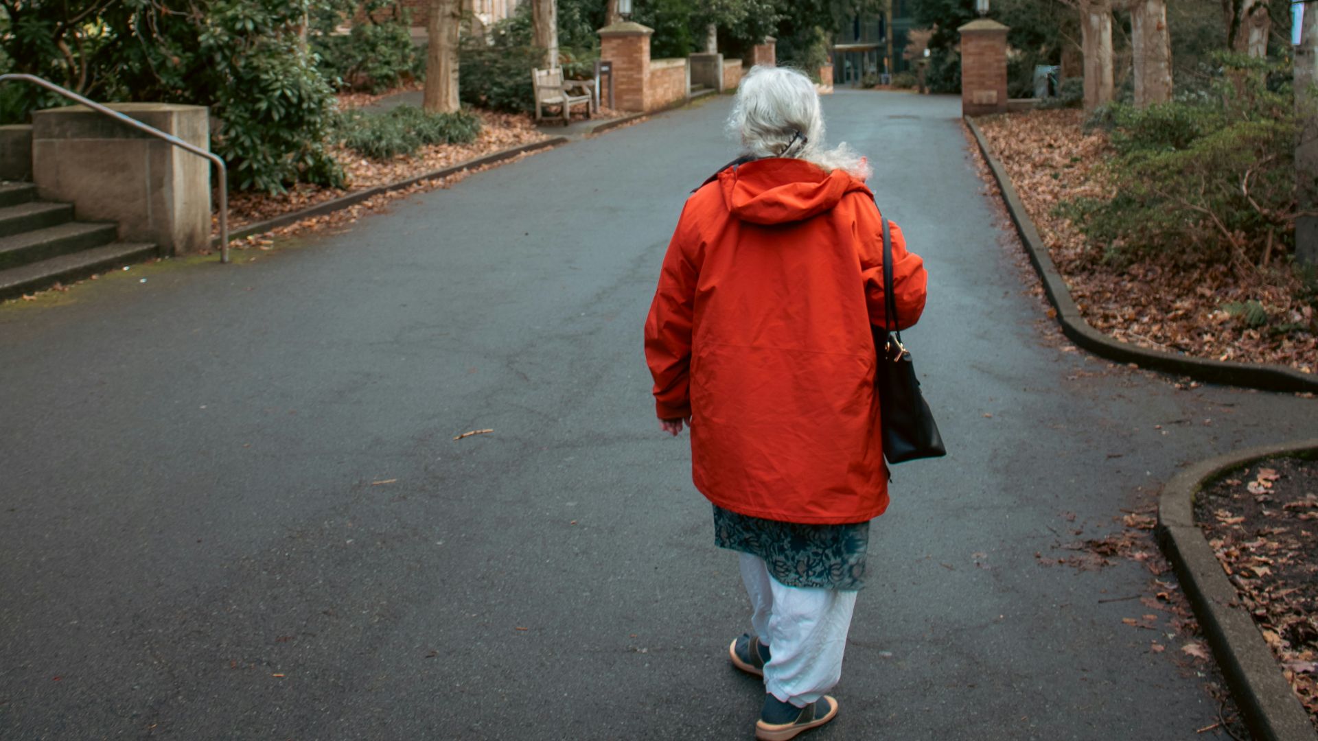 An elderly woman walks down a brick-lined street.