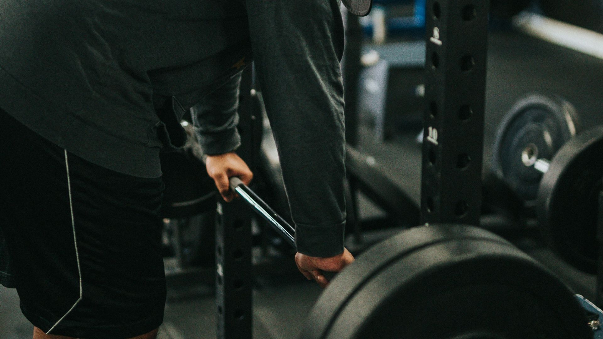 man in black t-shirt and black shorts carrying black barbell