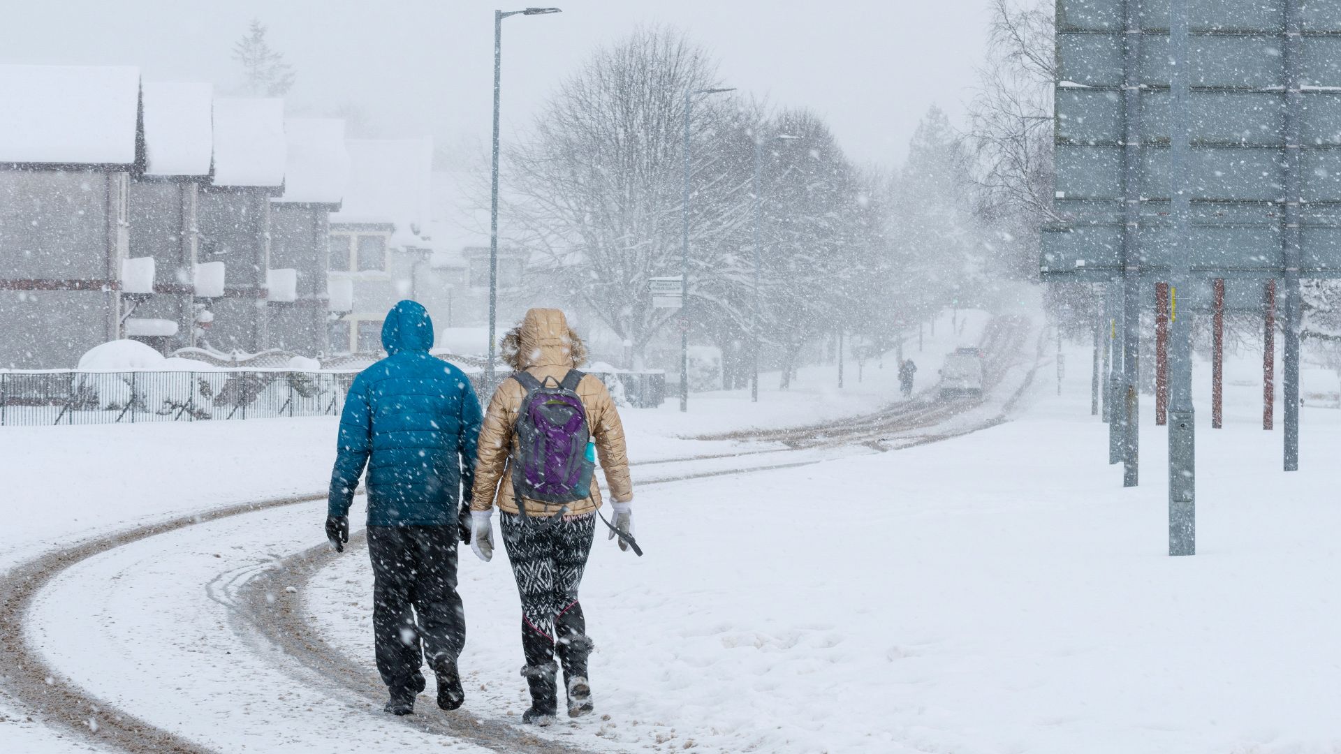2 person walking on snow covered road during daytime