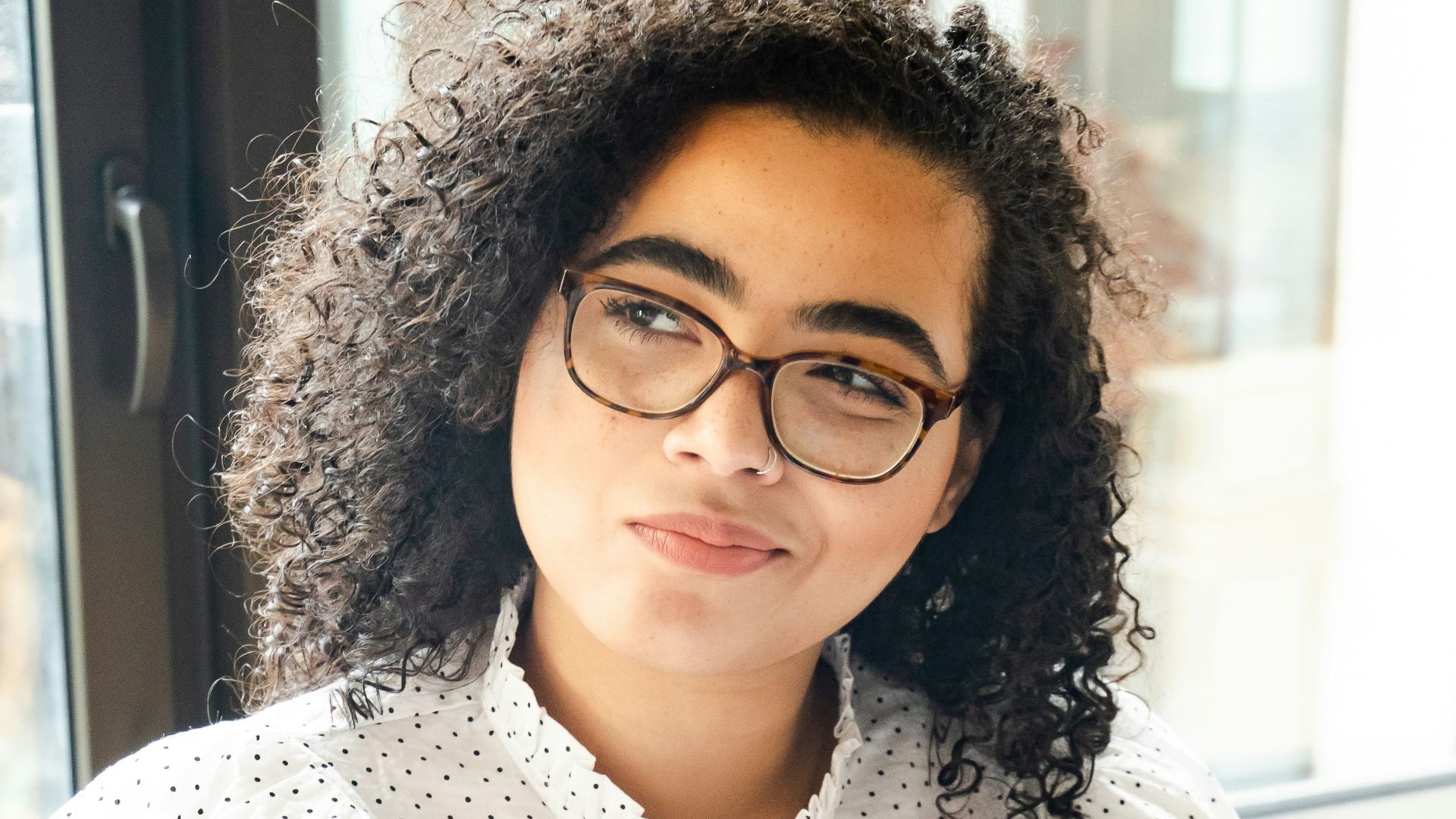 woman in white and black polka dot shirt holding blue and white book