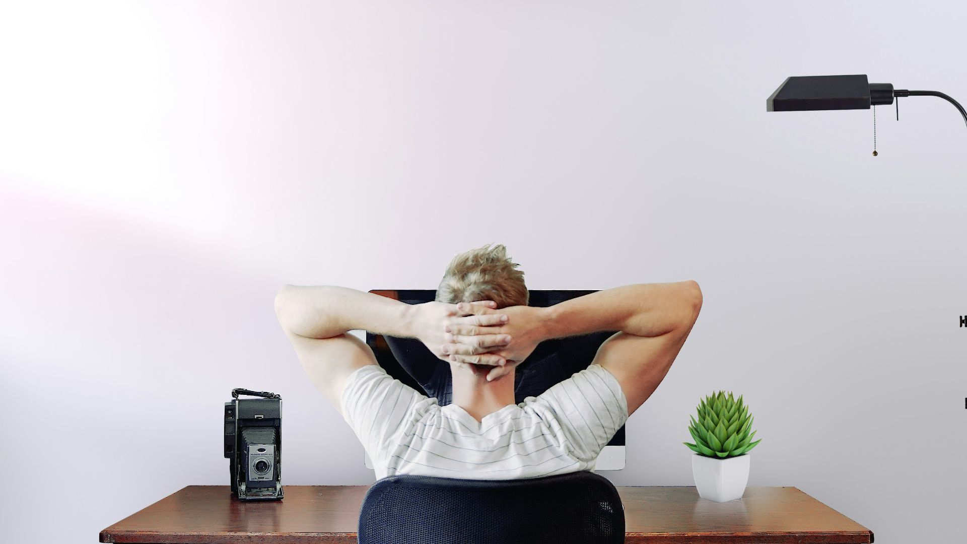 man holding his head while sitting on chair near computer desk