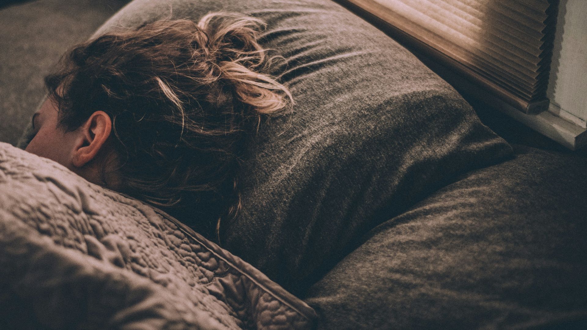 woman sleeping on bed under blankets