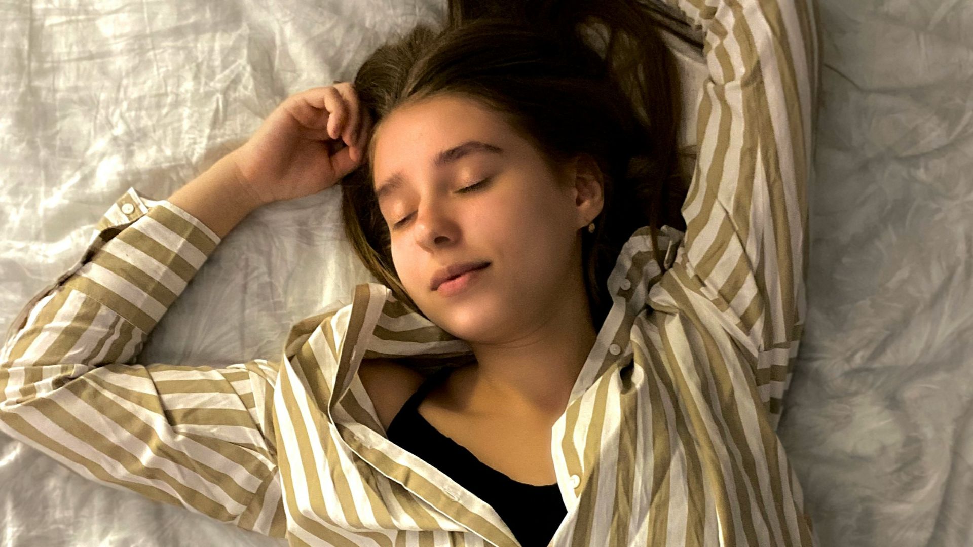 woman in white and black striped long sleeve shirt lying on bed