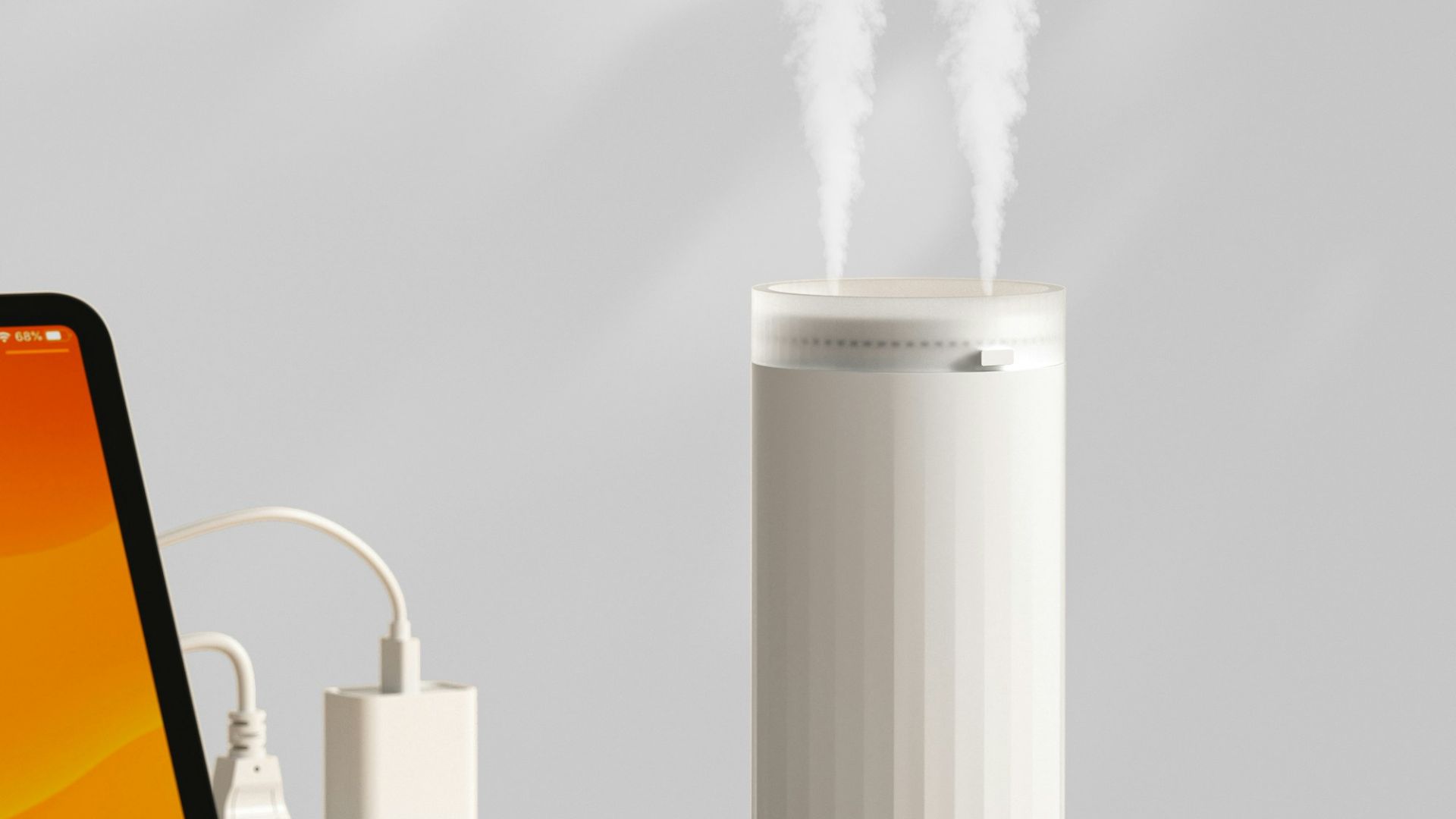 A white humidifier emits mist on a wooden desk.