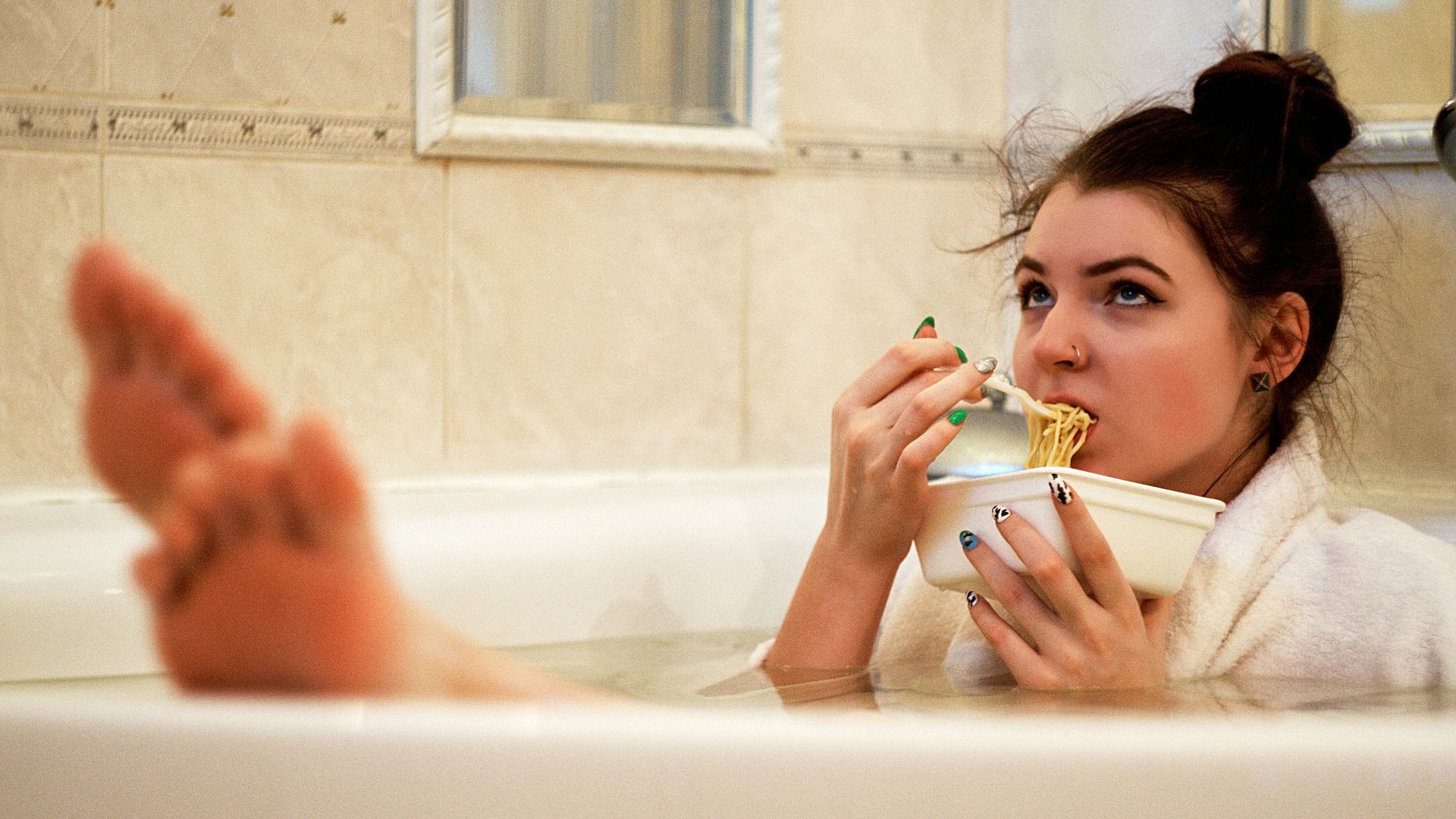 girl in bathtub holding white ceramic mug