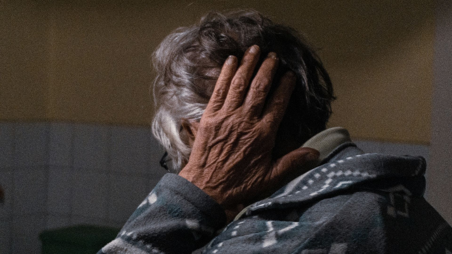 an older woman covering her face with her hands