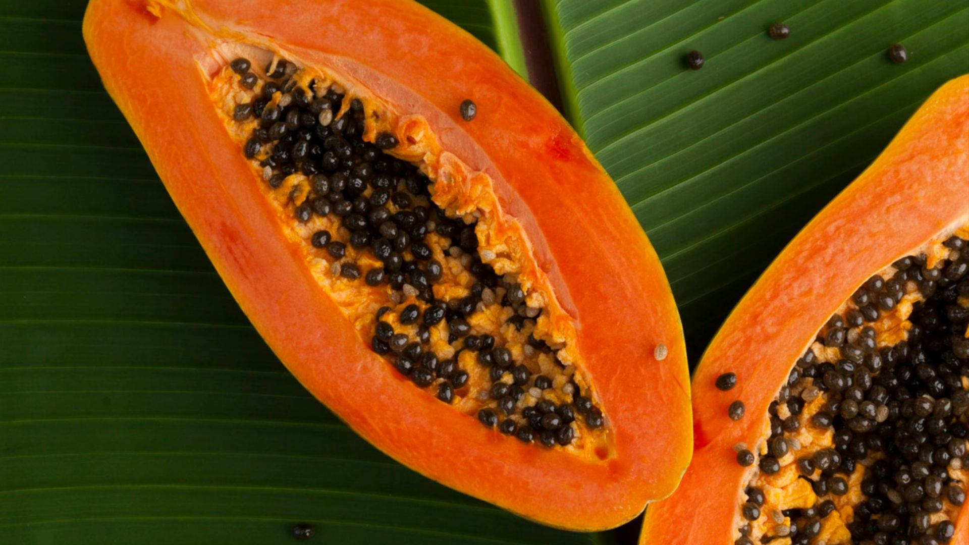 sliced papaya on green banana leaf