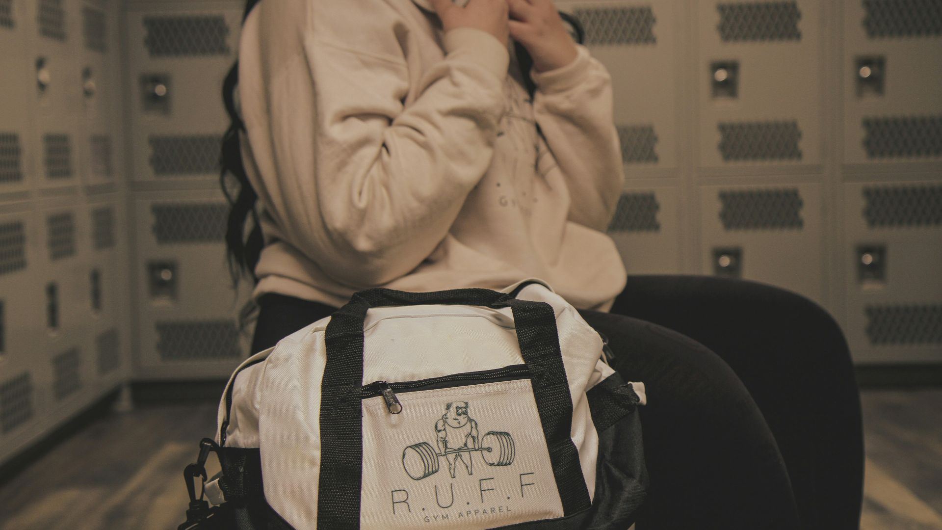 a woman sitting in a locker with a duffle bag