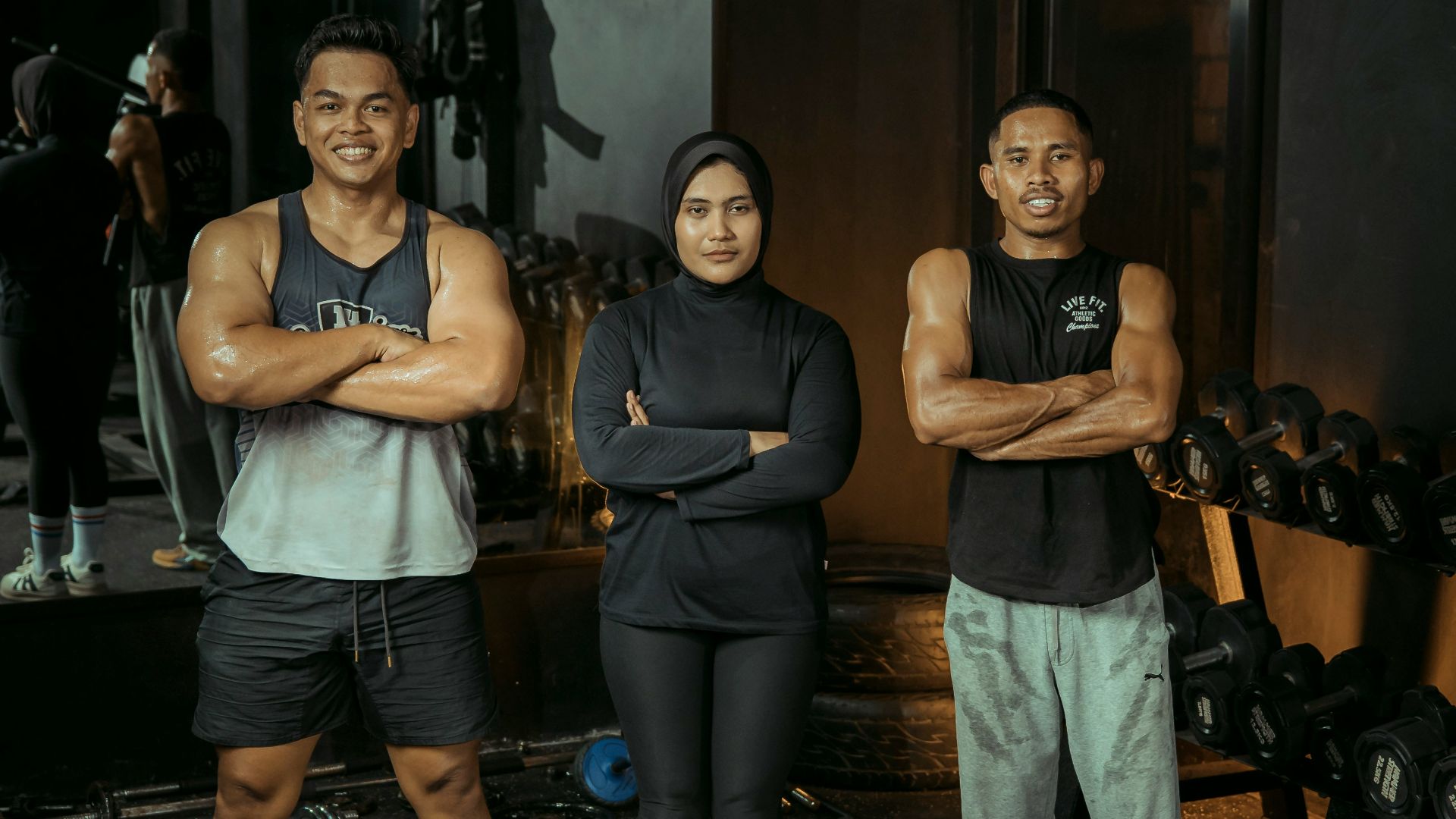 Three people pose at the gym.
