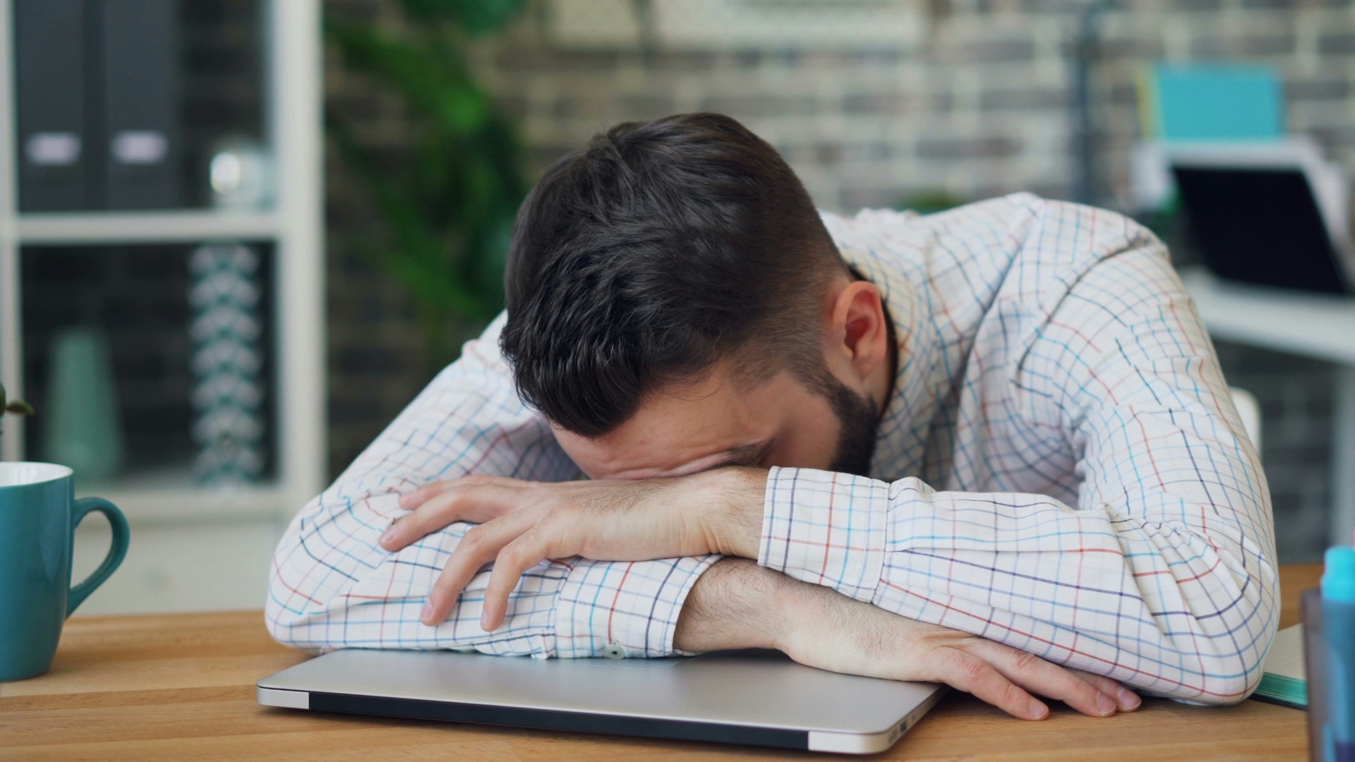 a man sitting at a desk with his head in his hands