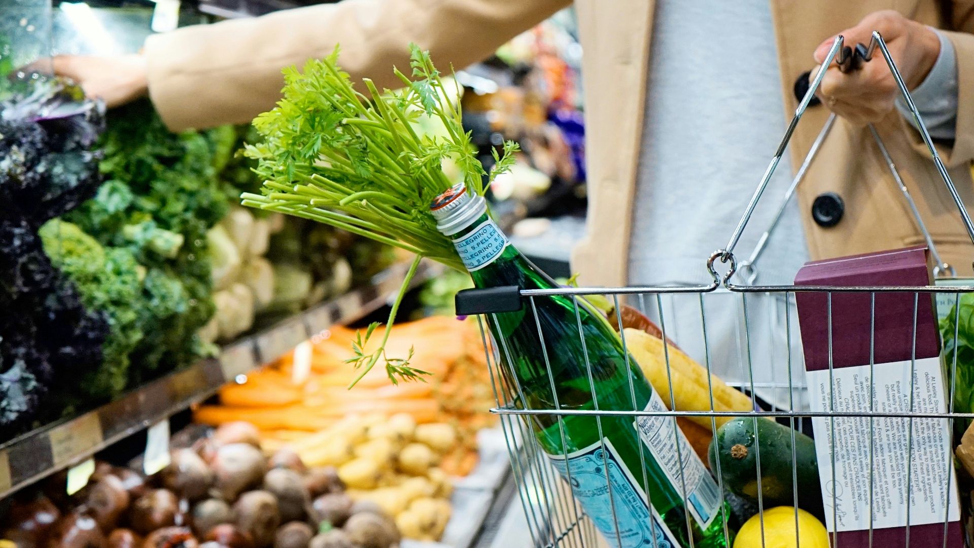 woman in white coat holding green shopping cart