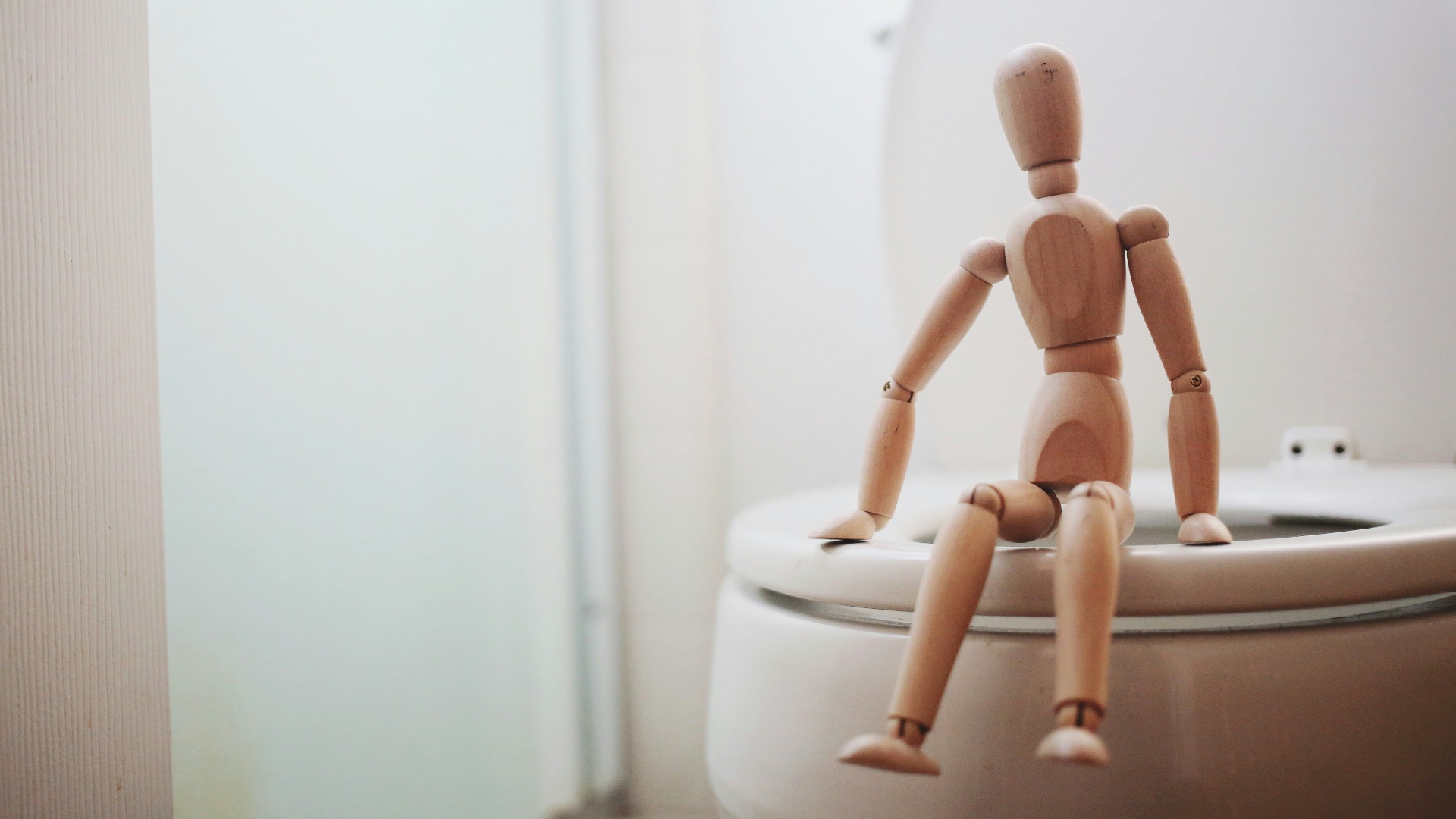 brown wooden doll on white ceramic toilet bowl