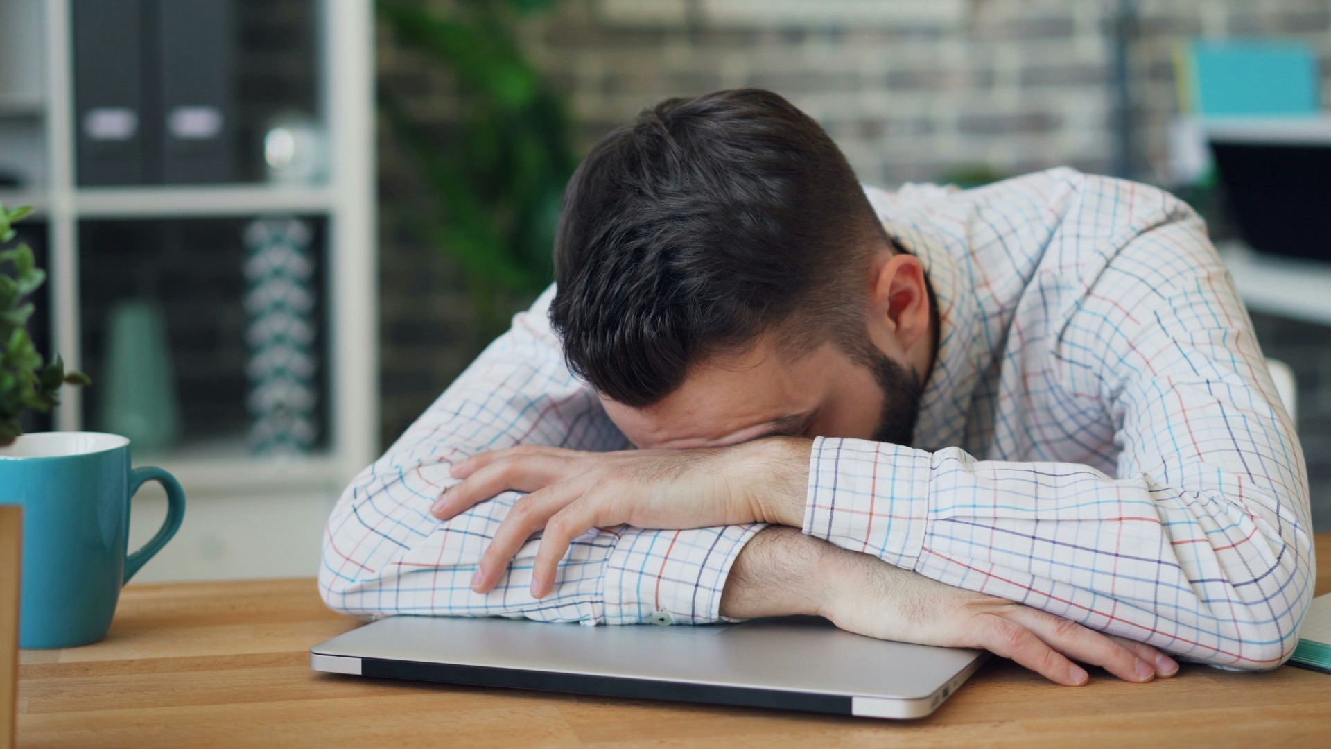a man sitting at a desk with his head in his hands