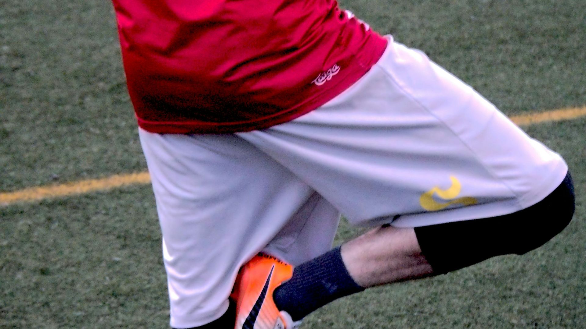 a man in a red and yellow uniform kicking a soccer ball