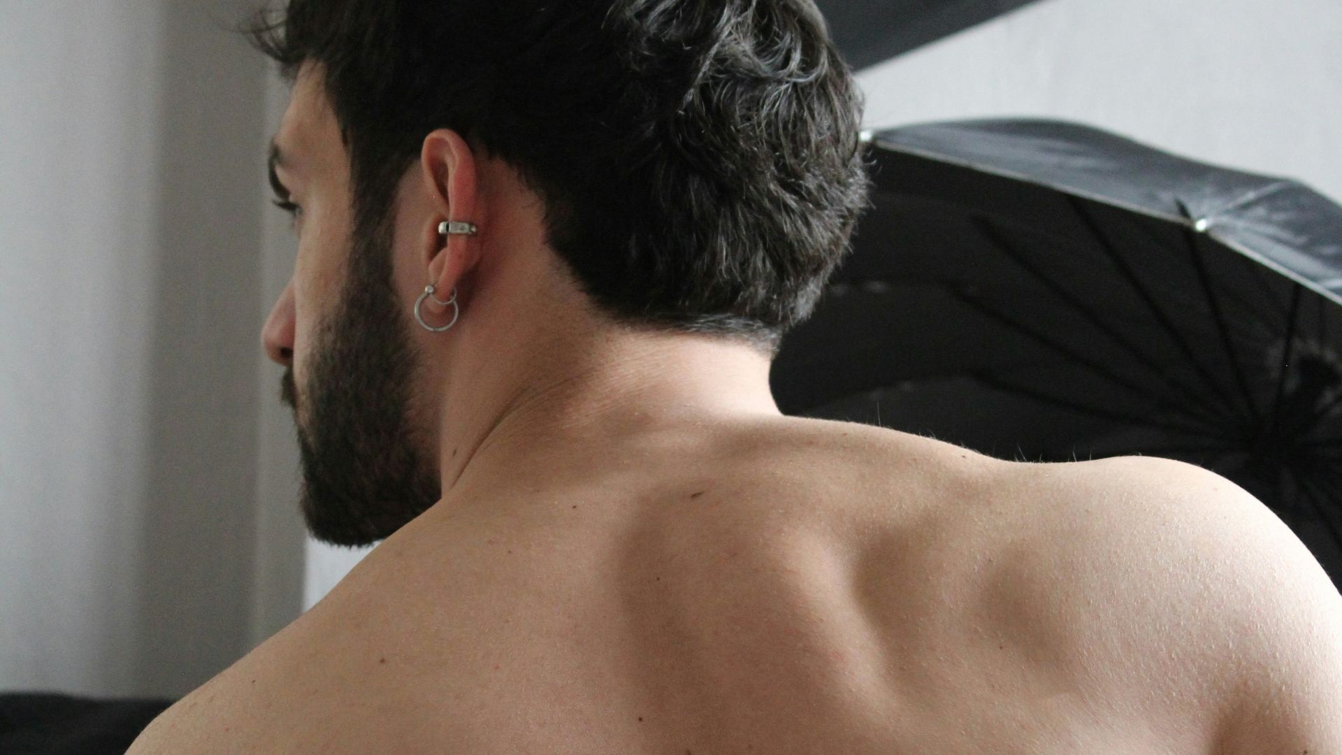 a man with no shirt standing in front of a black umbrella