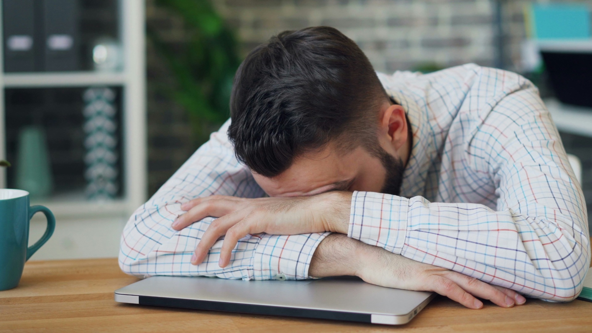 a man sitting at a desk with his head in his hands