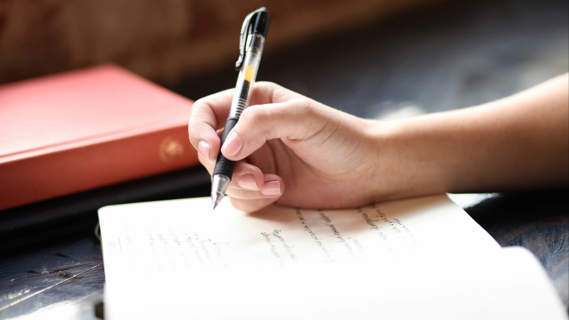 a person writing on a piece of paper with a pen