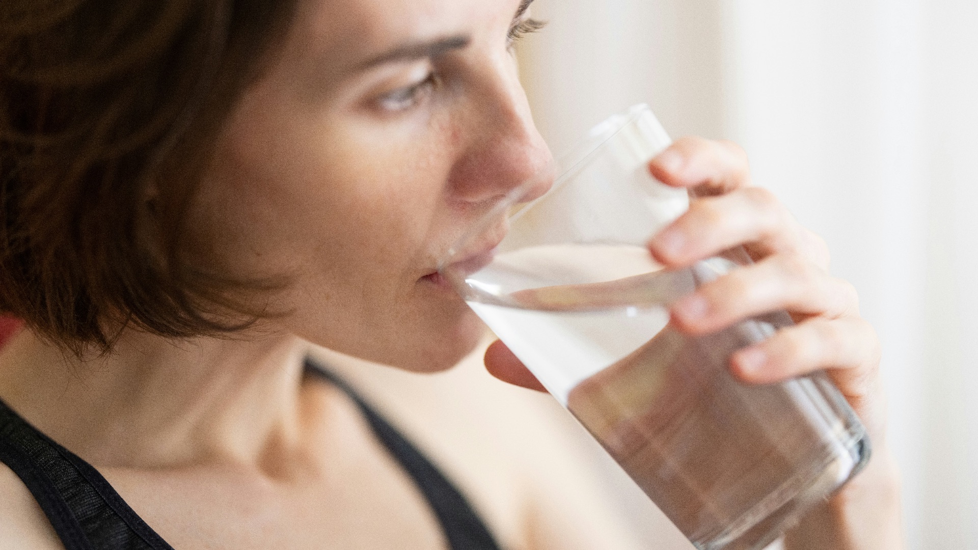 woman in black tank top drinking water