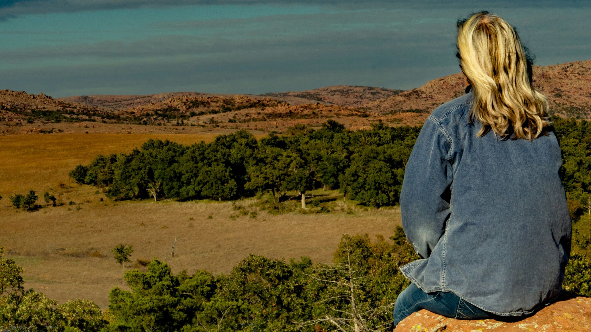 a woman sitting on top of a large rock