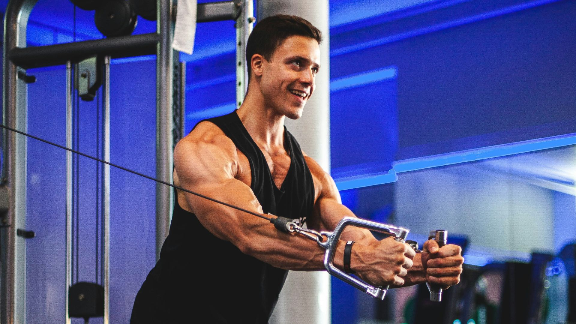 man in black tank top and gray shorts holding black smartphone