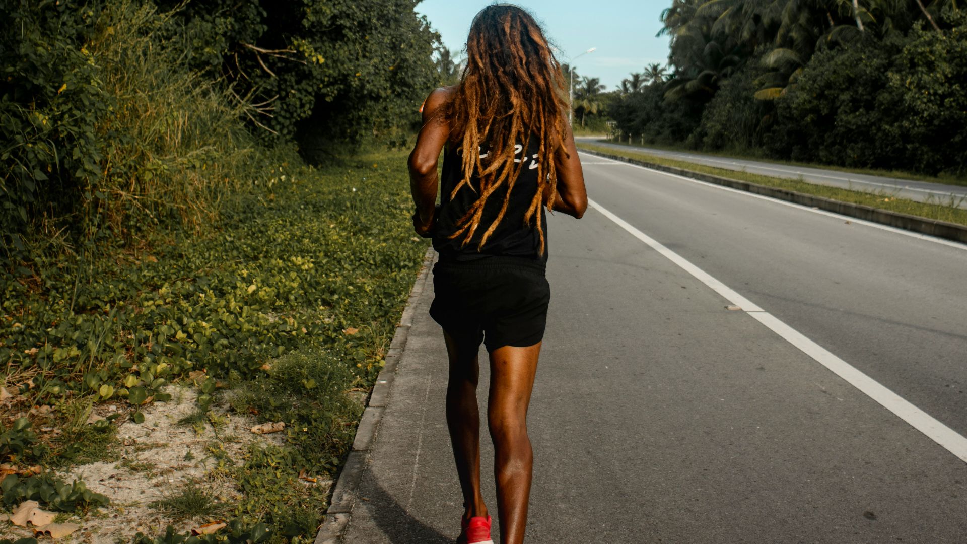 woman in black dress walking on the road during daytime