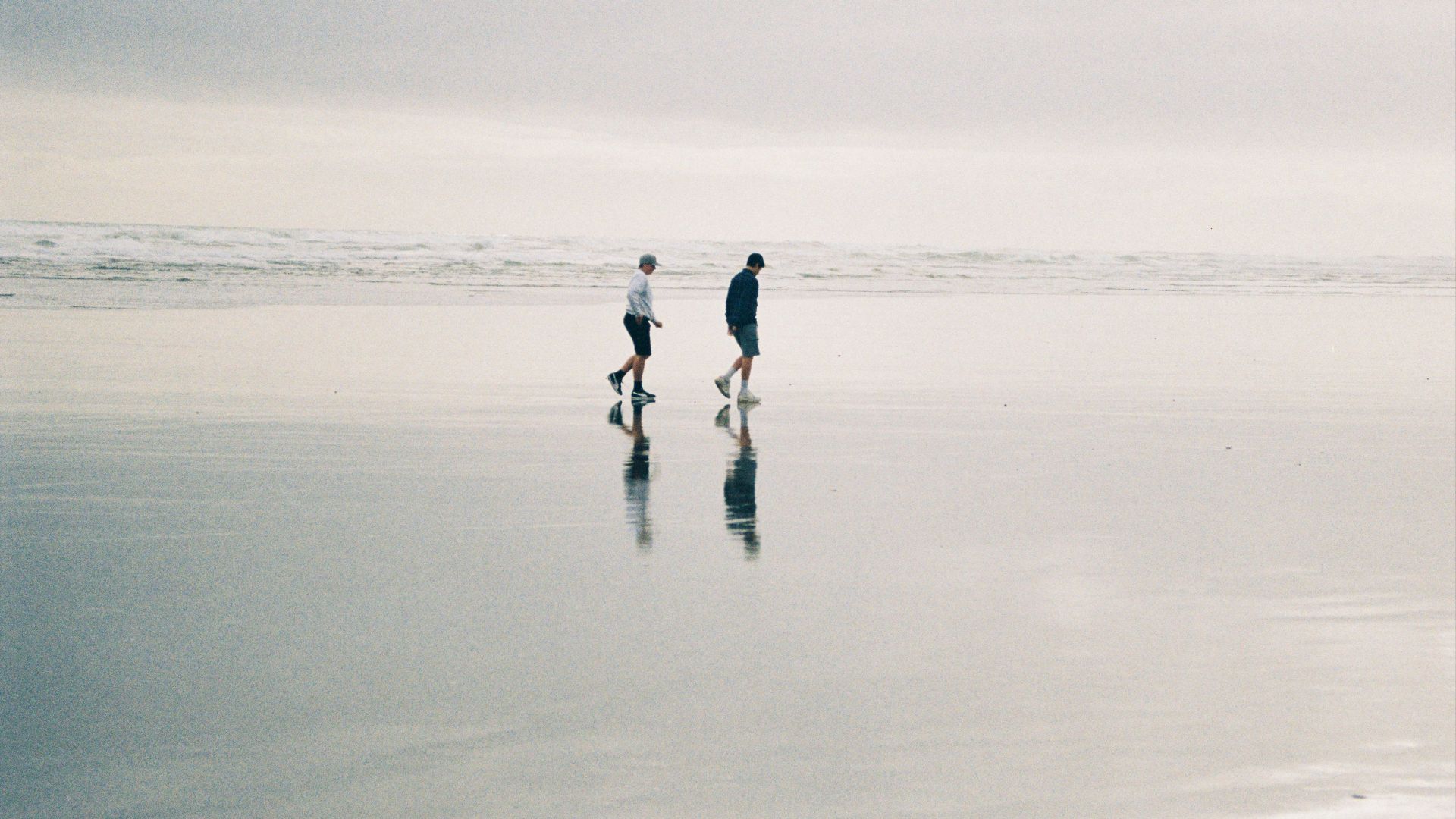 two person walking at beach during daytime