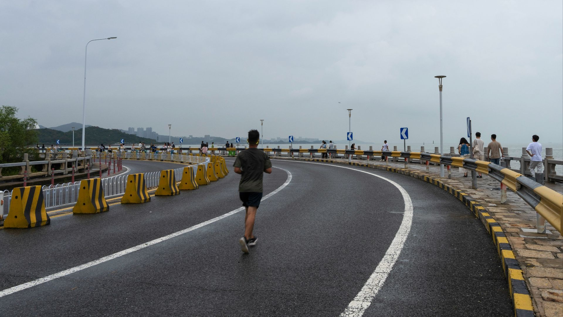 A person running on a road beside the ocean.