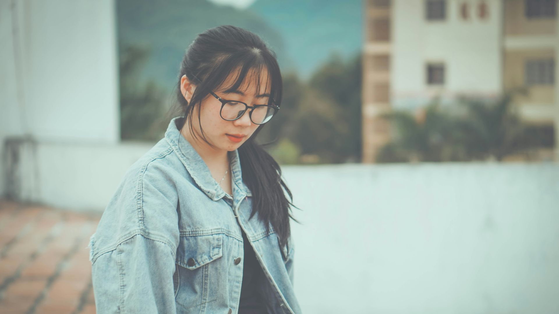 a woman wearing glasses and a denim jacket