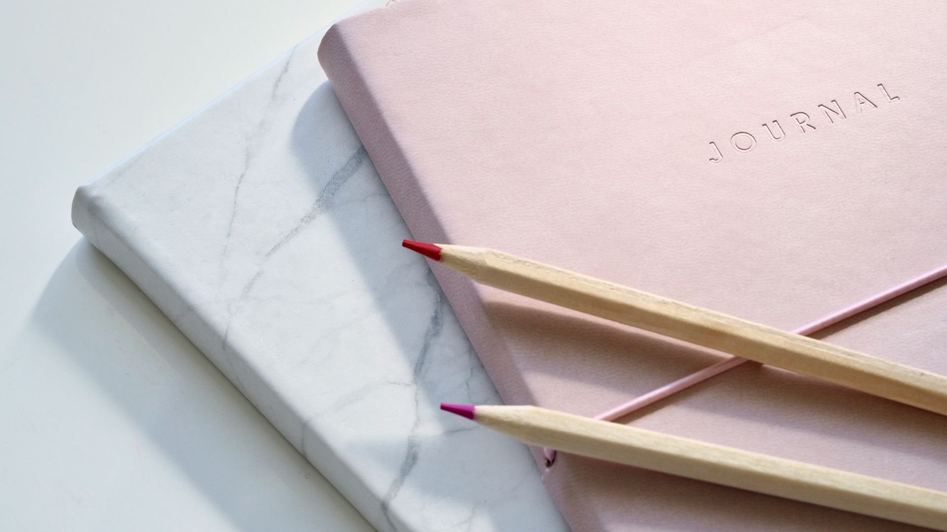 red and purple coloring pencils on pink journal