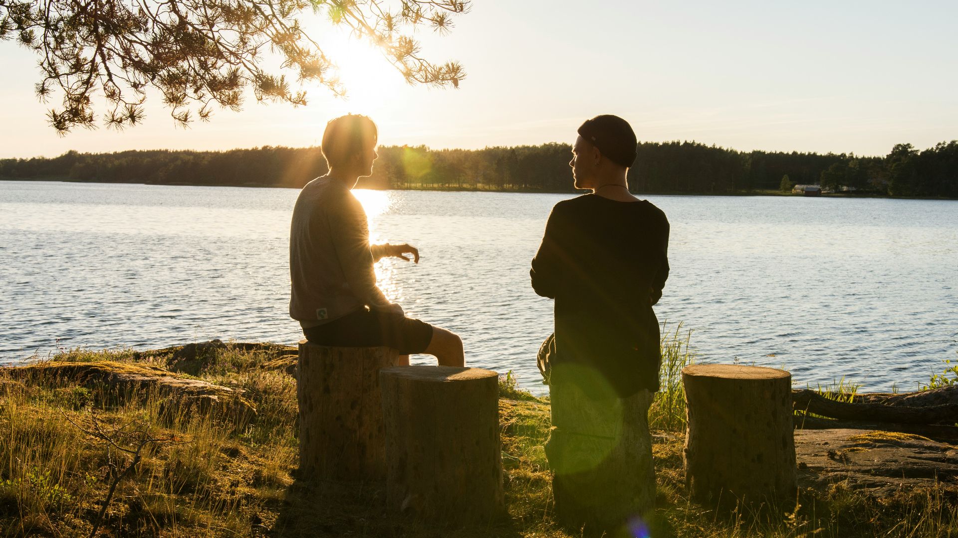 man in black jacket standing beside body of water during sunset