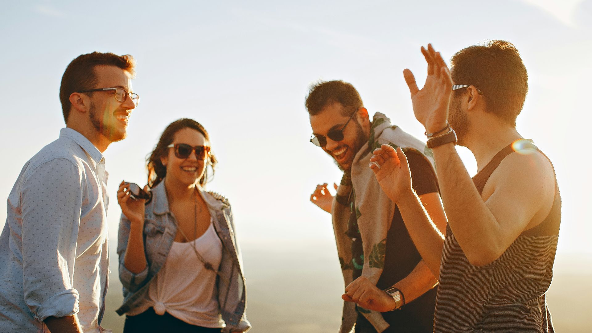 three men and one woman laughing during daytime