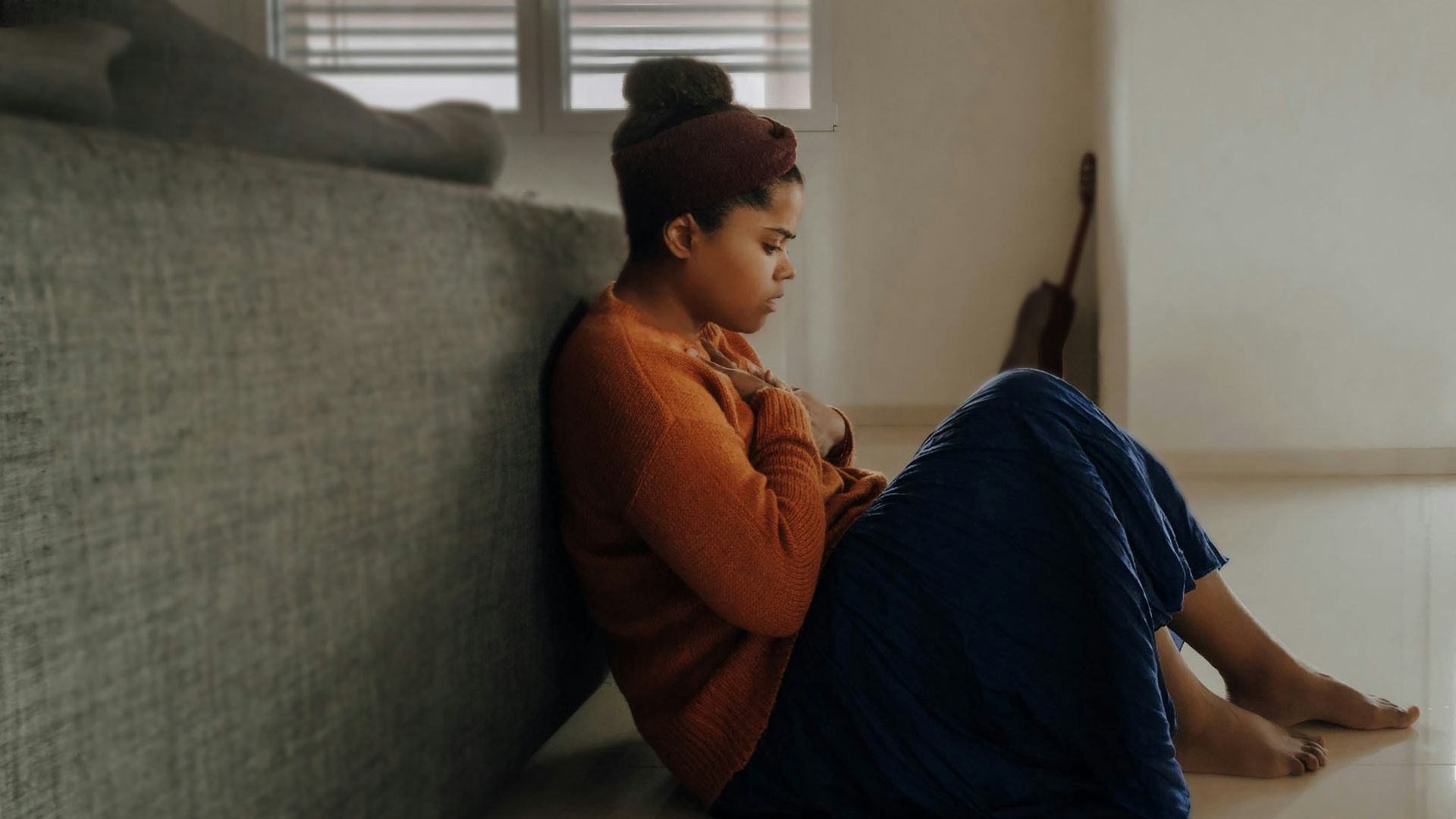 man in orange long sleeve shirt sitting on gray couch