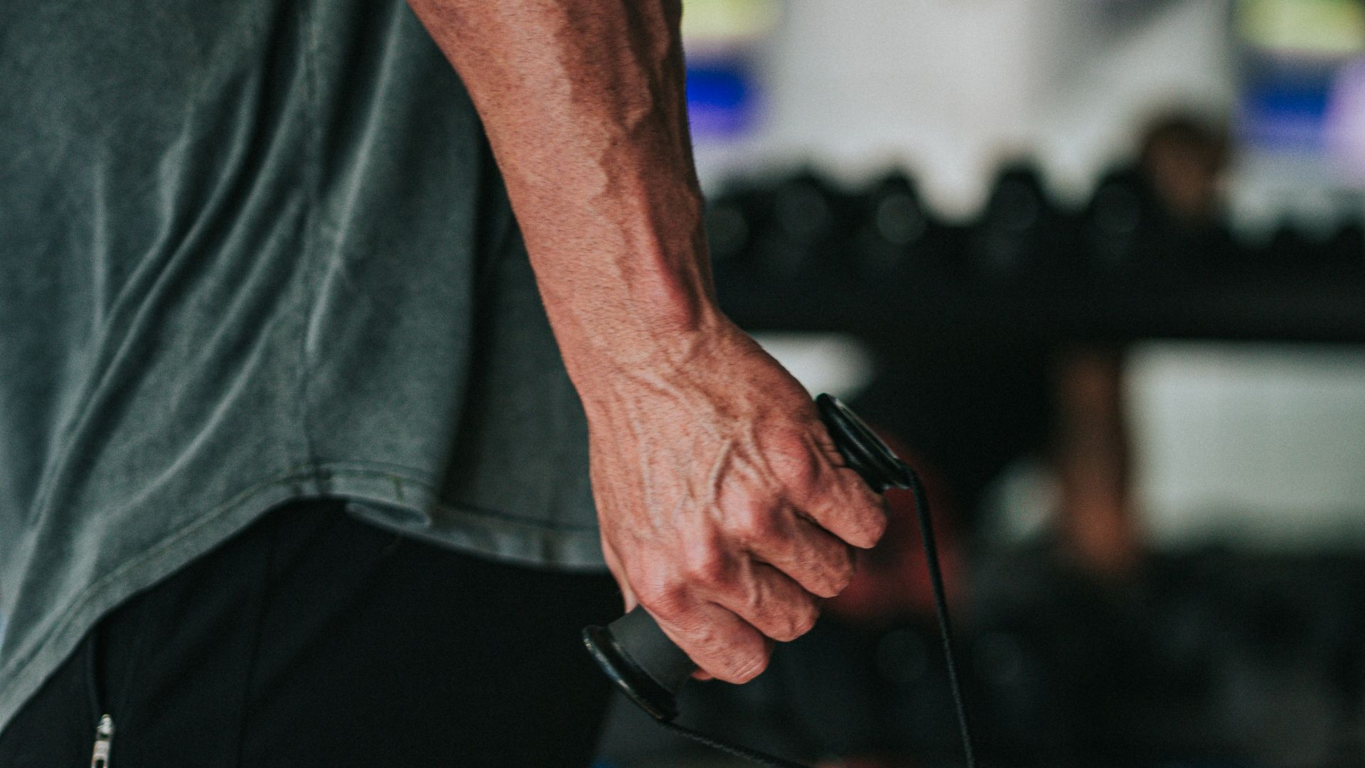man in gray t-shirt and black pants holding black corded headphones