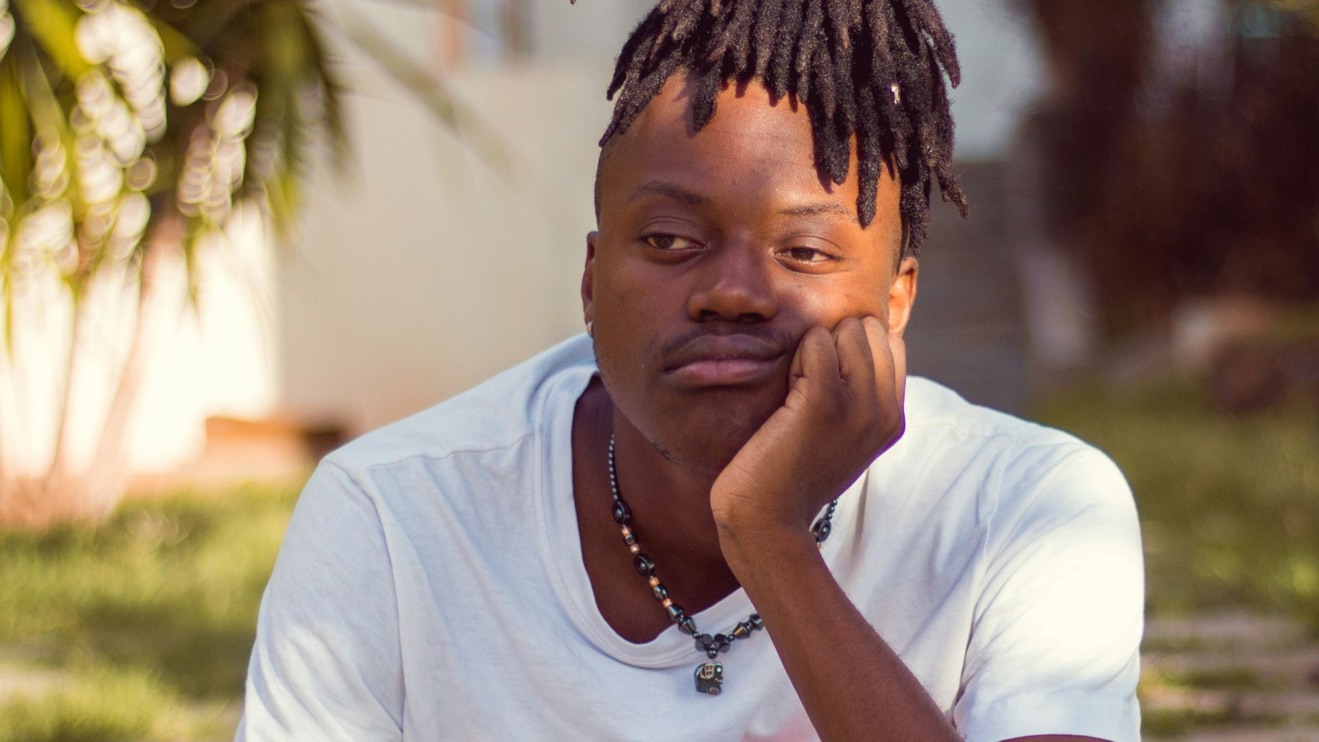 man in white crew neck t-shirt sitting on brown wooden chair