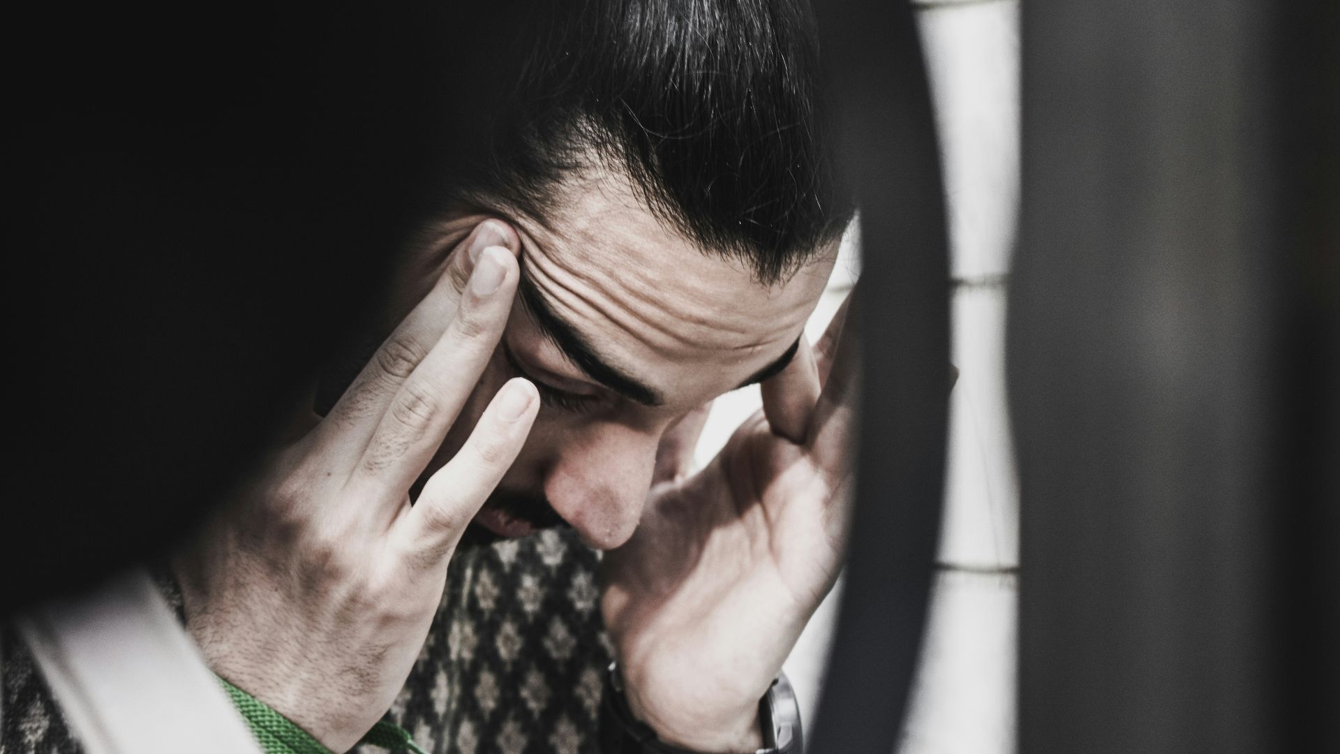 man holding his temples and looking down
