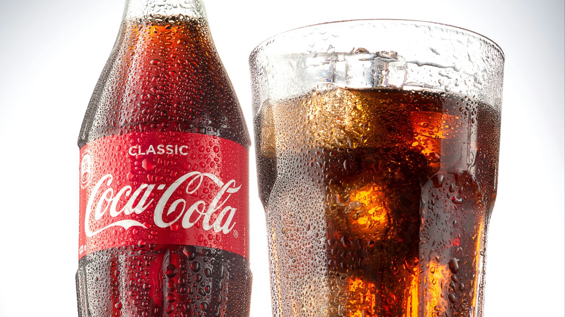 coca cola bottle beside drinking glass