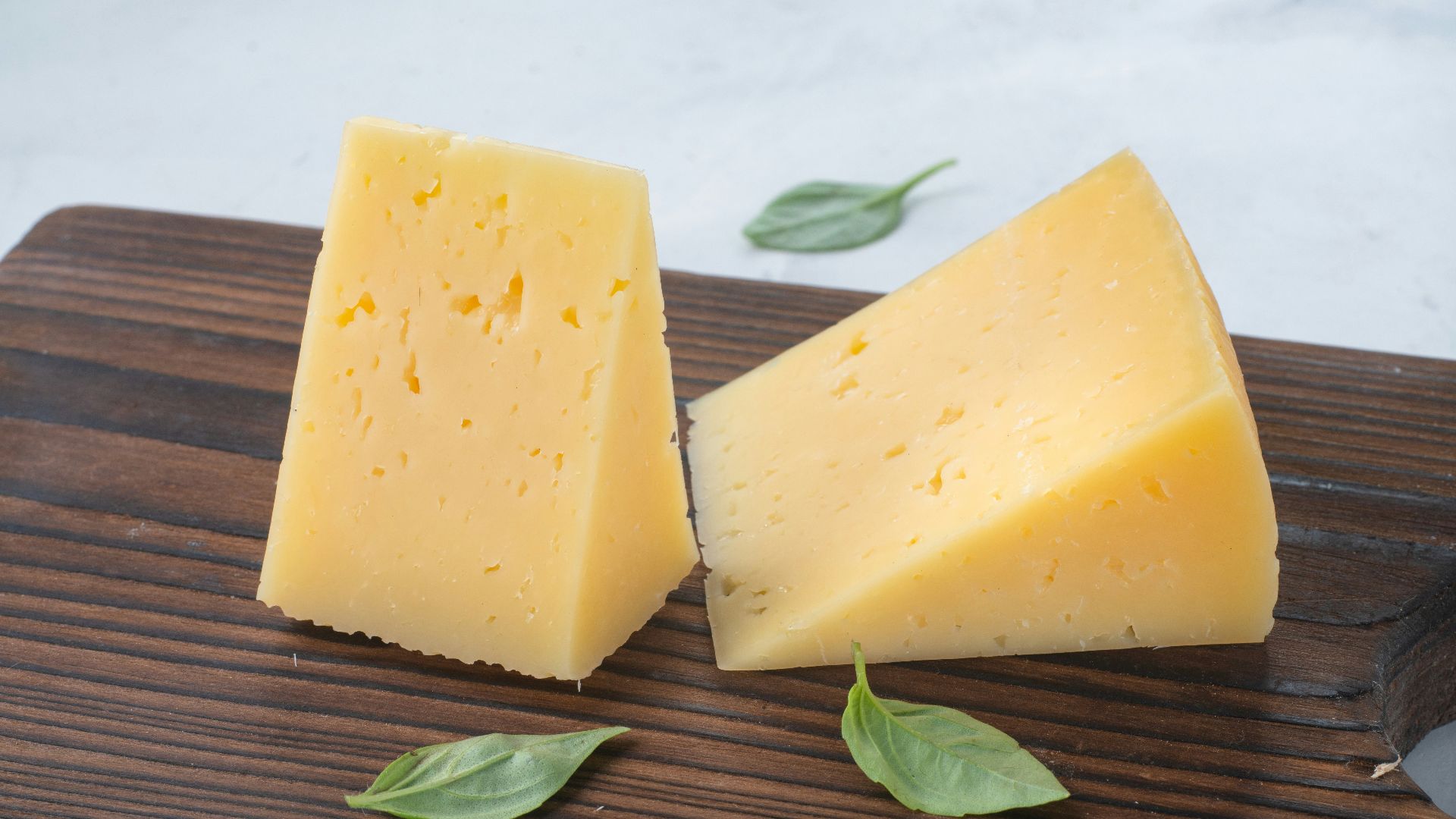 a couple of pieces of cheese sitting on top of a wooden cutting board
