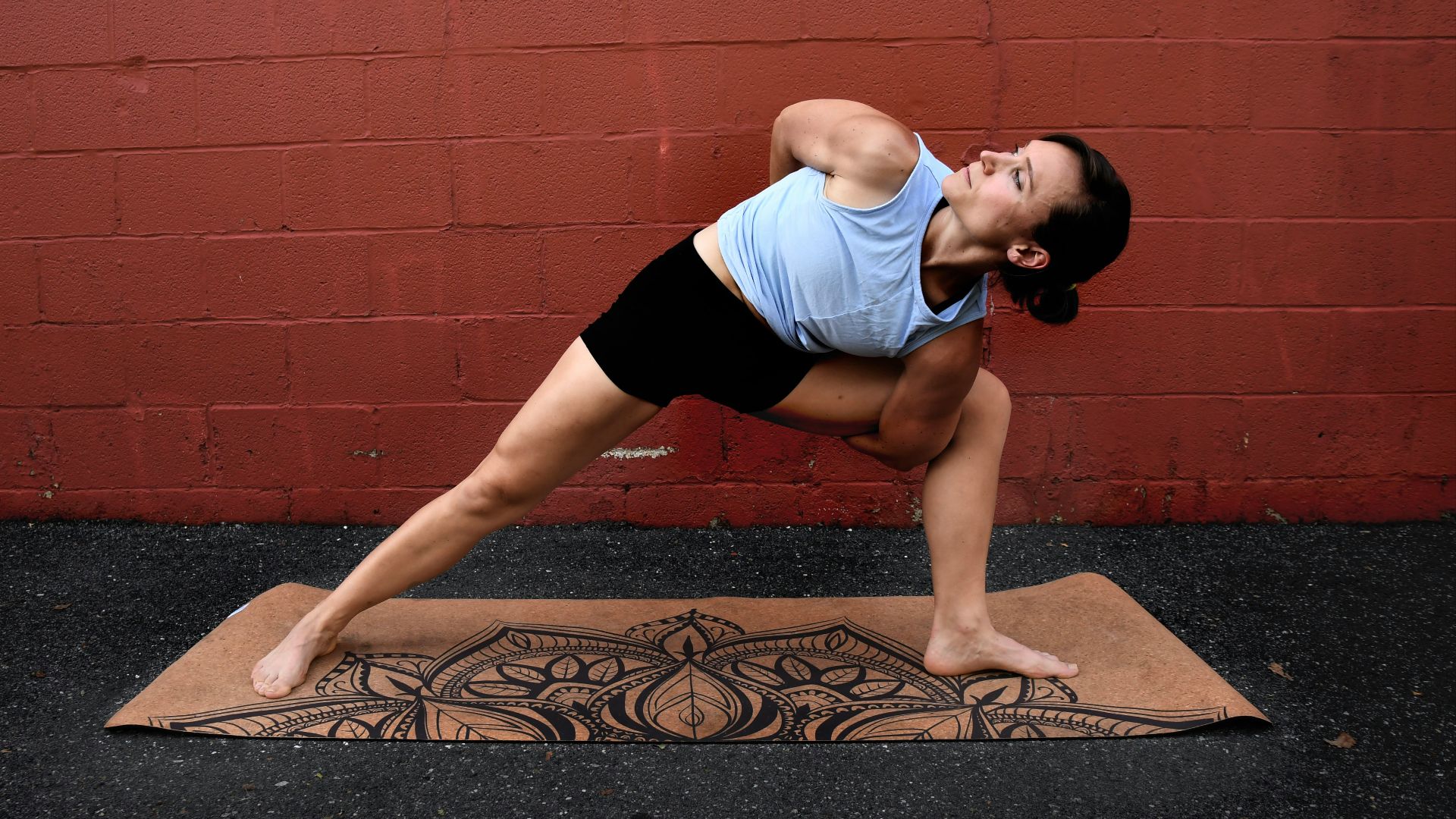 woman in white tank top and black shorts doing yoga on brown concrete floor