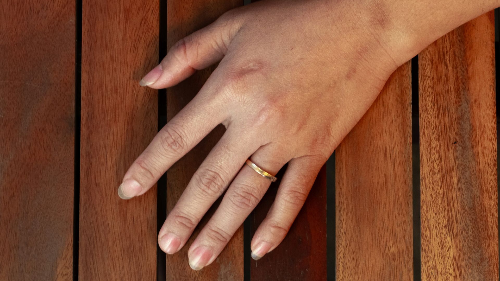 A woman's hand resting on a wooden table