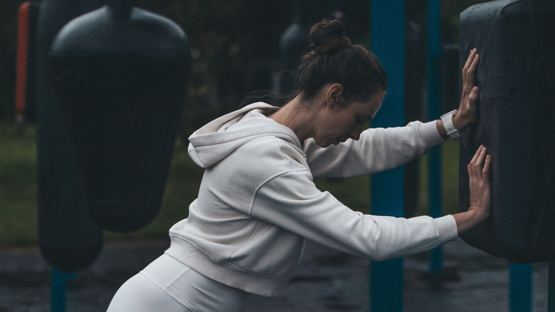 A woman stretches at an outdoor boxing gym.