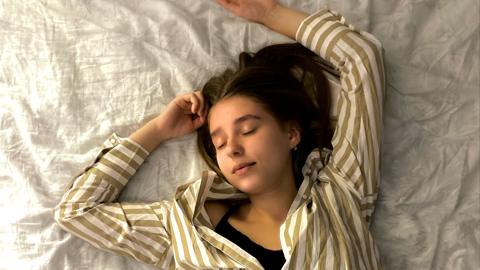 woman in white and black striped long sleeve shirt lying on bed