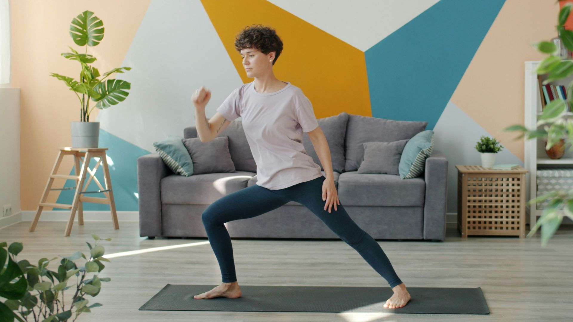 Woman exercising on yoga mat in living room.