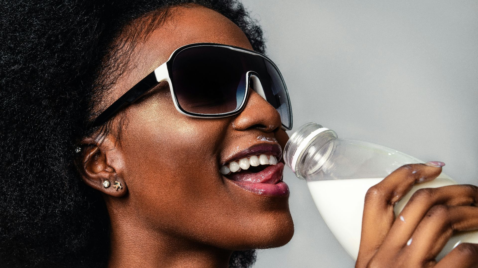 woman wearing black and white sunglasses drinking milk