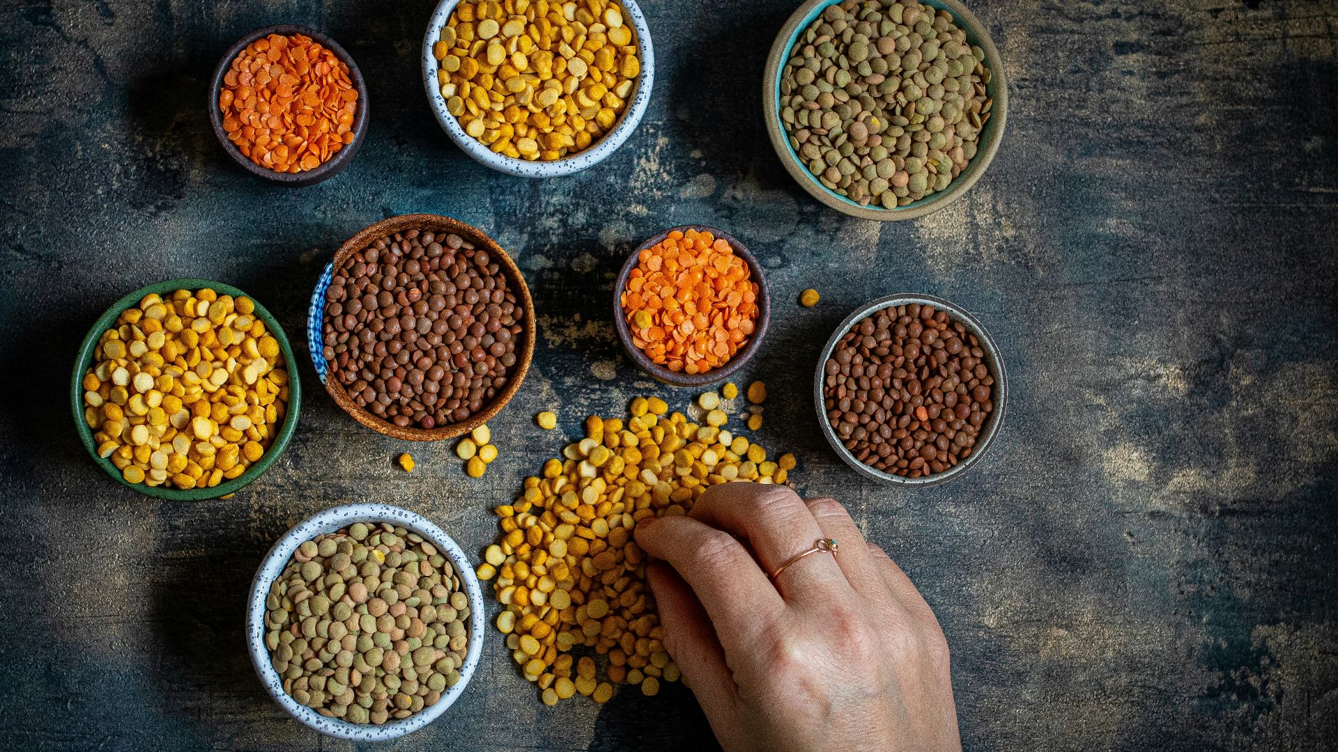 a person touching a bowl of lentils on a table