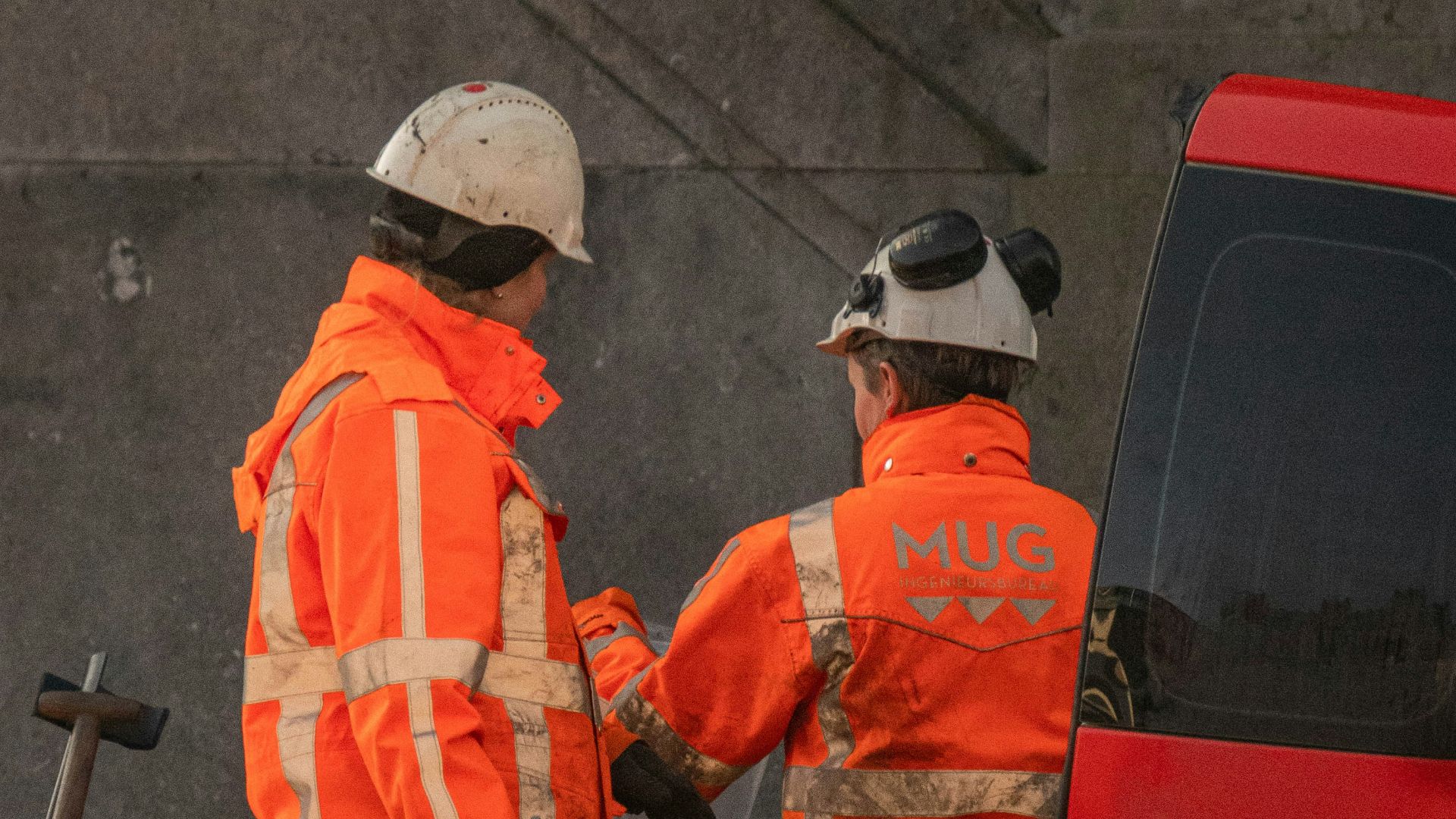 a couple of men standing next to a red bus