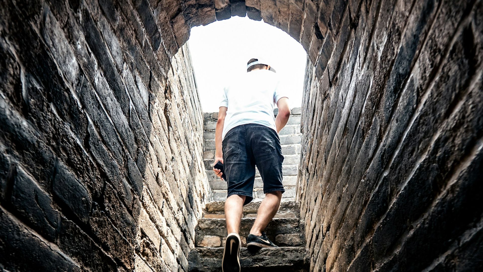 person in white t-shirt and black shorts walking outside of tunnel