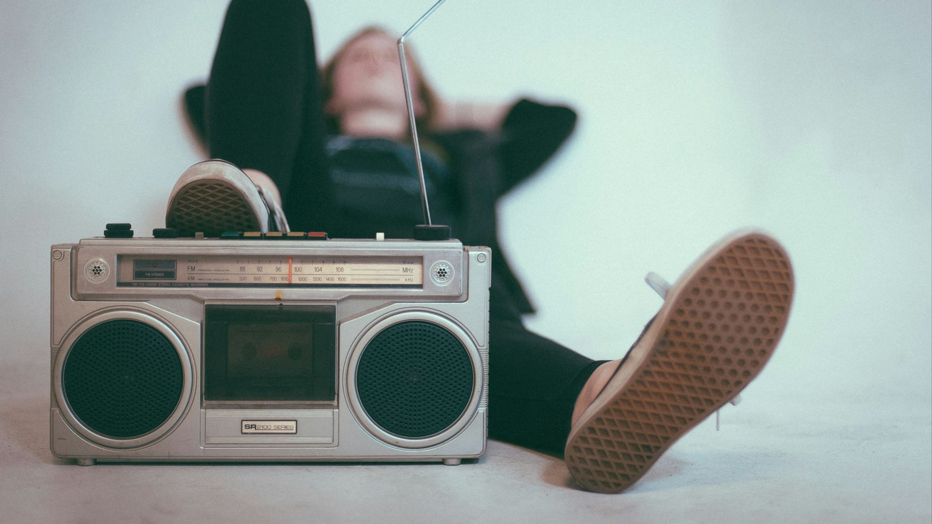 woman laying on bed near gray radio