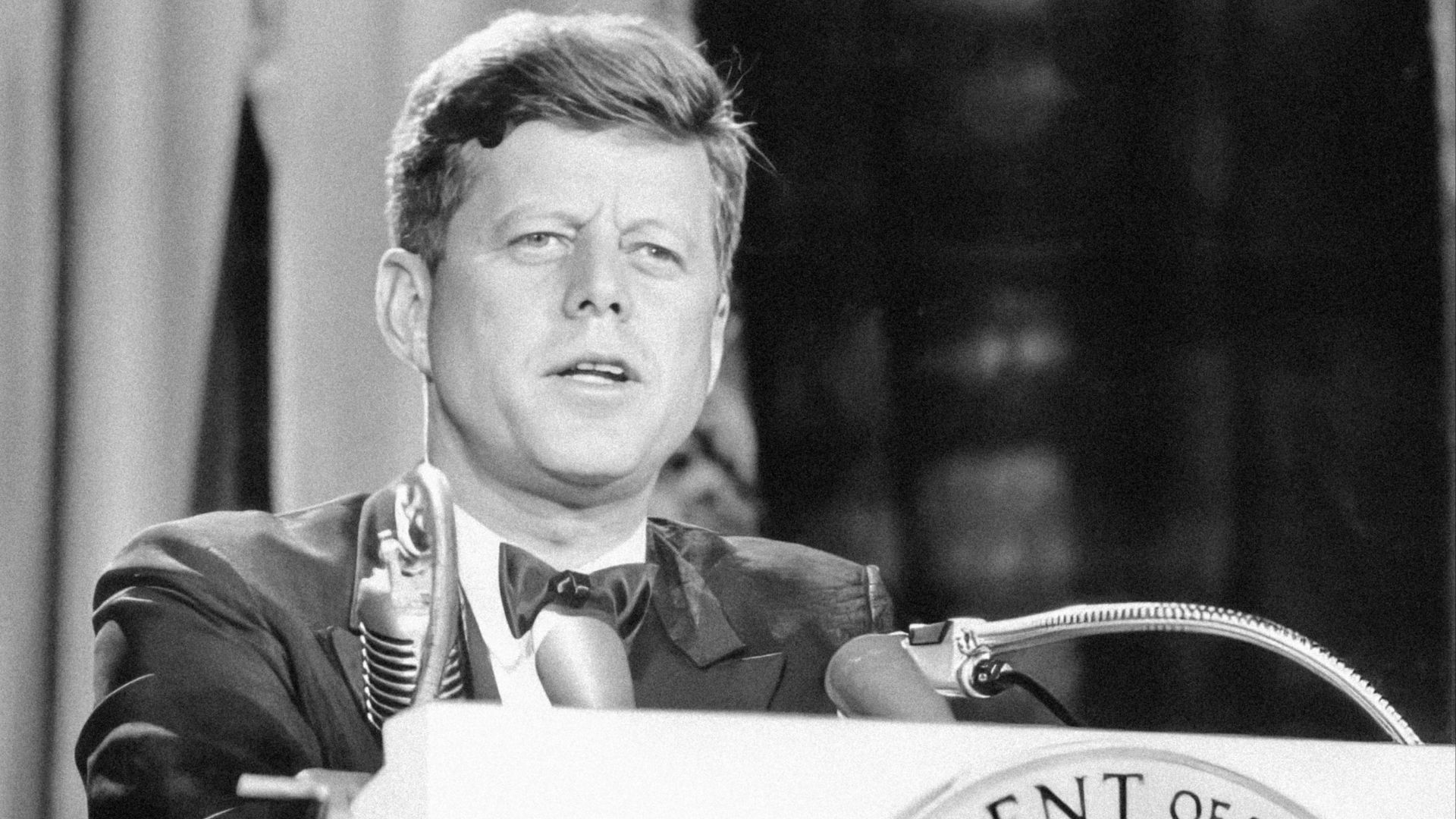 a man in a suit and tie standing at a podium
