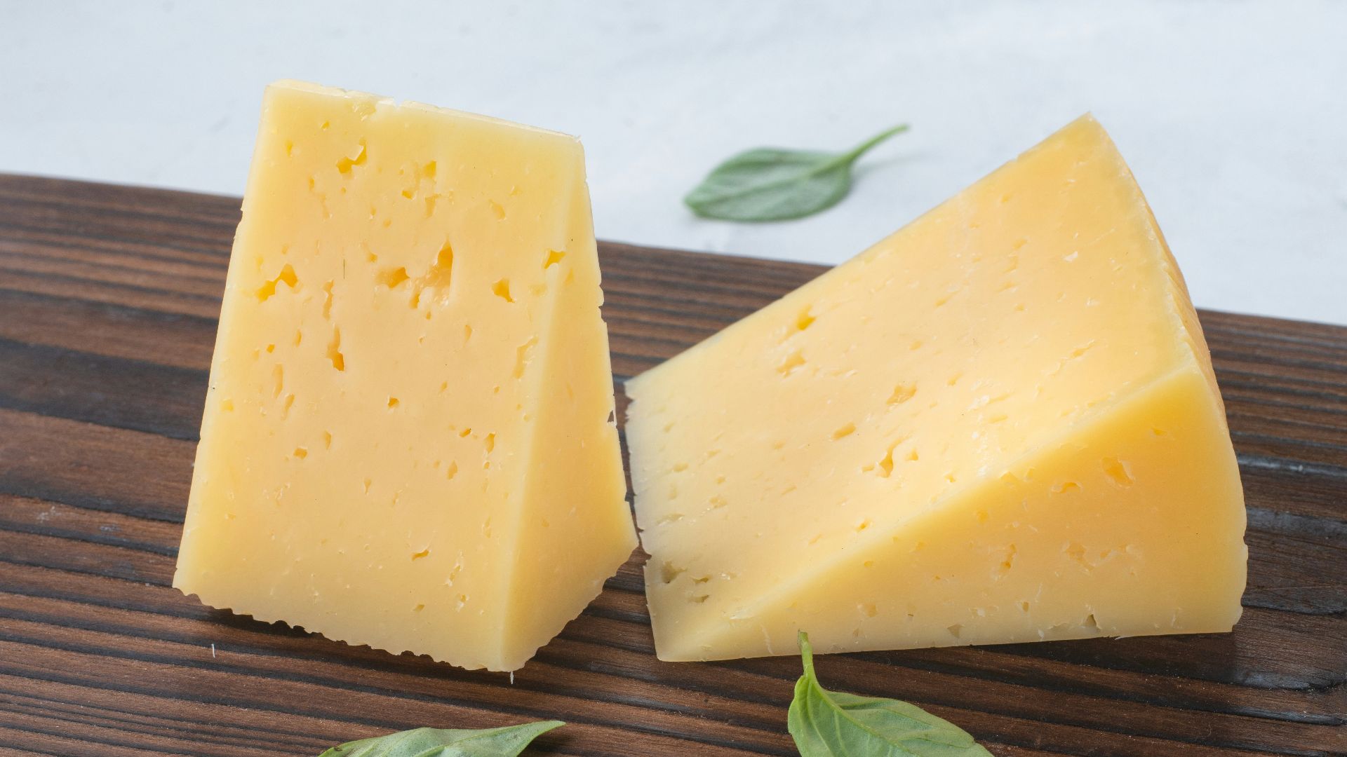 a couple of pieces of cheese sitting on top of a wooden cutting board