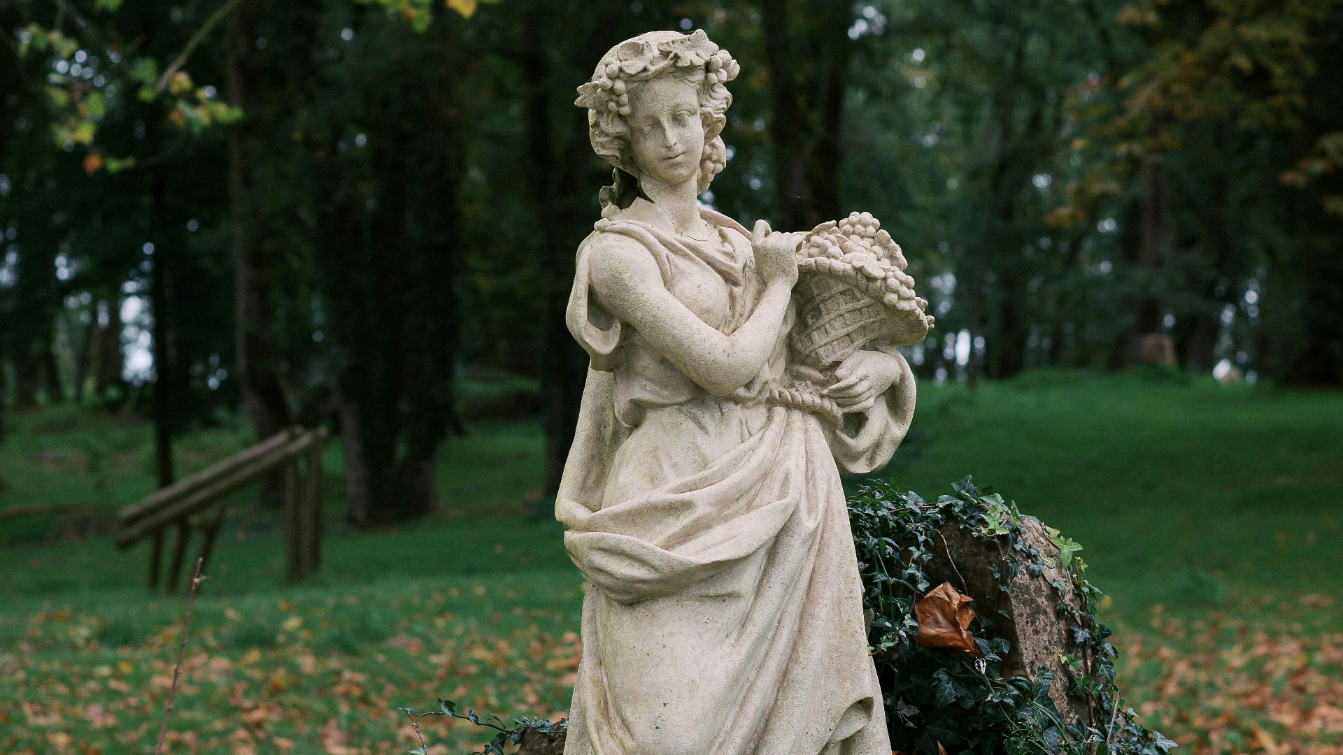 A statue of a woman holding a book in a park